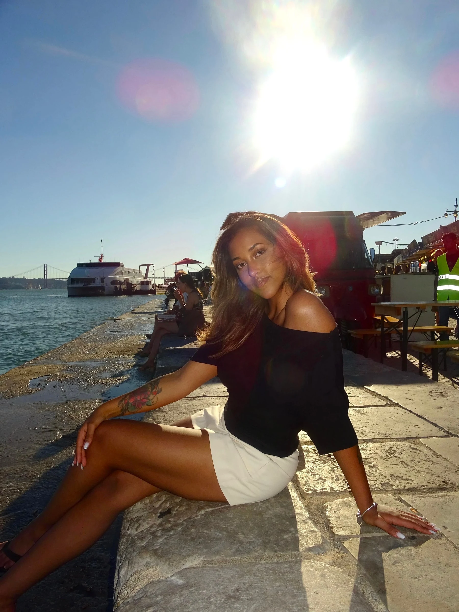 Rafaela sitting on a stone quay by the water in the evening sun